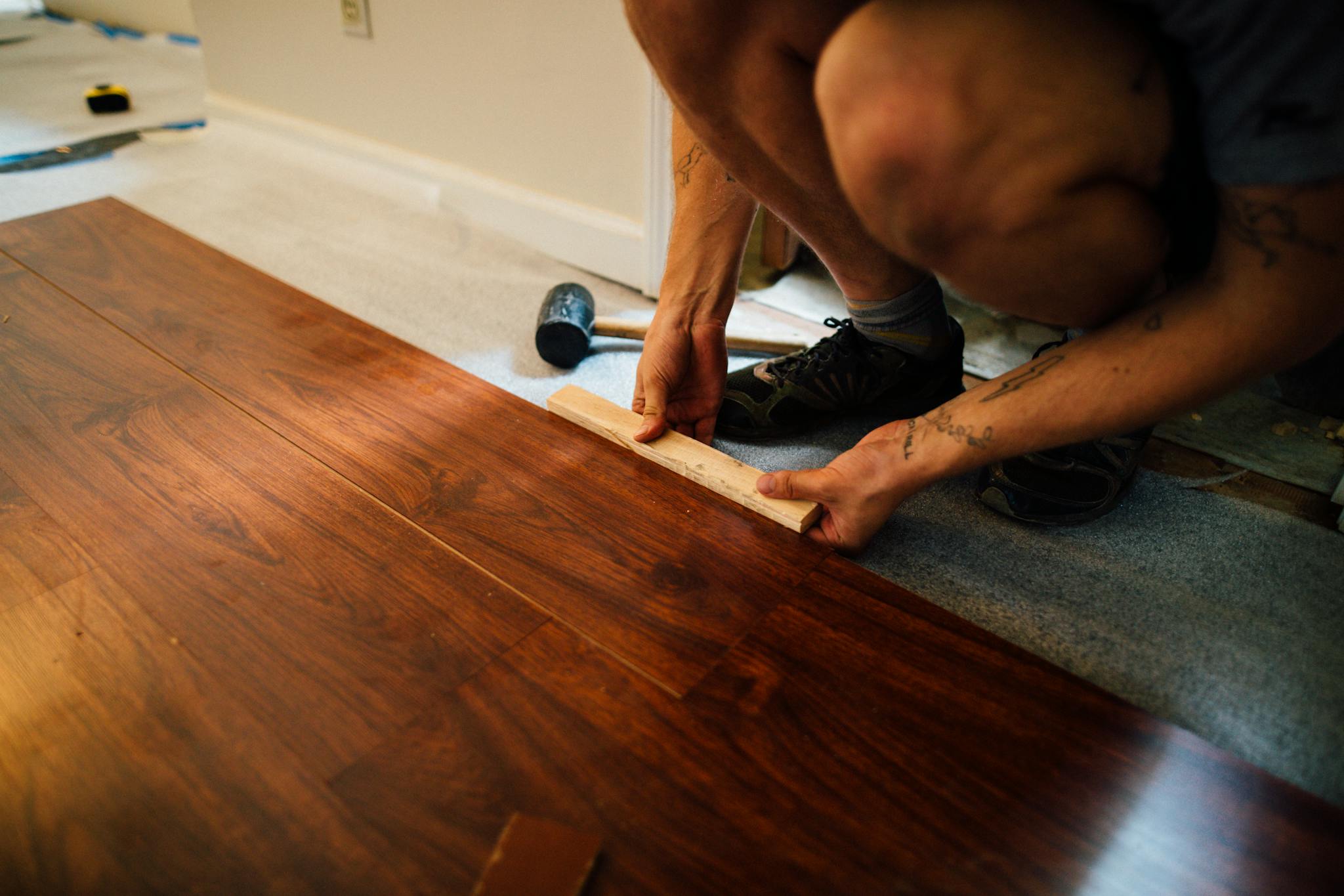 Laminate or Vinyl Flooring Expert lays wooden floor indoors, showcasing precise craftsmanship and modern interior renovation.